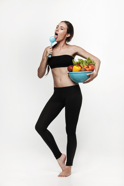 Portret van jonge fit vrouw groenten eten  - Foto, afbeelding
