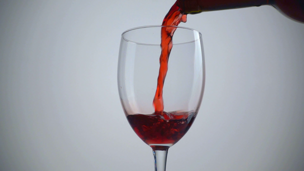 Rotwein über weißem Hintergrund ins Glas gießen. Zeitlupe - Filmmaterial, Video