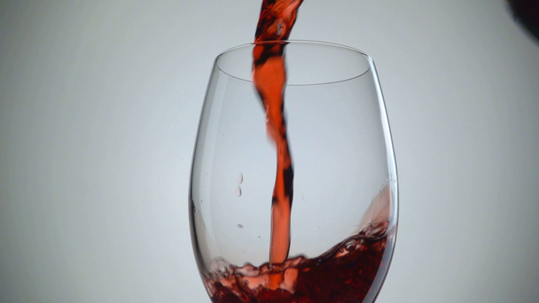 Öntés vörös bor az üveg fehér háttérhez képest. Lassú mozgás - Felvétel, videó
