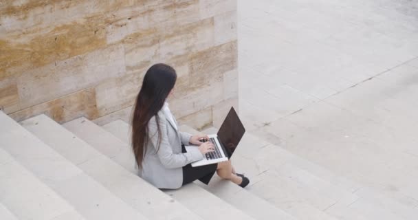 Üzletasszony ül a márvány lépcsőház, a laptop - Felvétel, videó