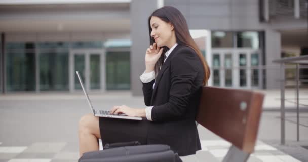 kobieta pracuje na laptopie na ławce na zewnątrz - Materiał filmowy, wideo