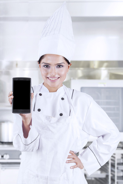 Chef showing smartphone in kitchen - Foto, afbeelding
