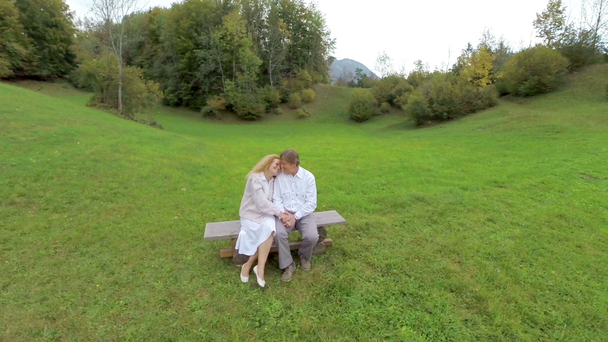ζευγάρι που κάθεται σε ένα παγκάκι στη φύση - Πλάνα, βίντεο