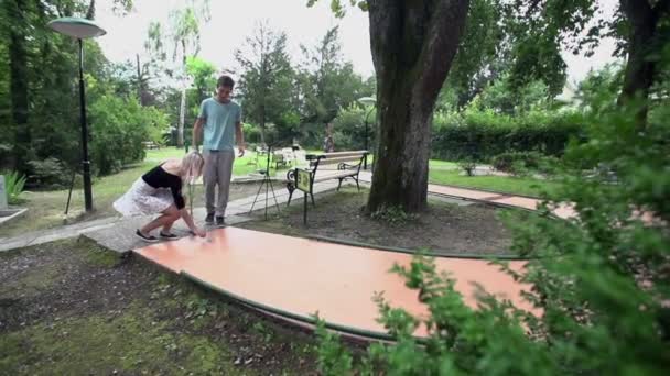 Couple at next mini golf course setting ball - Footage, Video