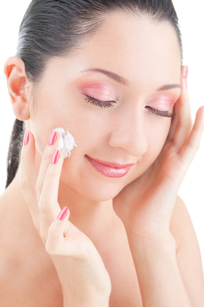 Woman applying cream to her face on the white background - Foto, imagen