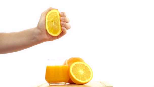 Mano exprimida naranja fresca en un vaso de jugo de naranja
 - Imágenes, Vídeo