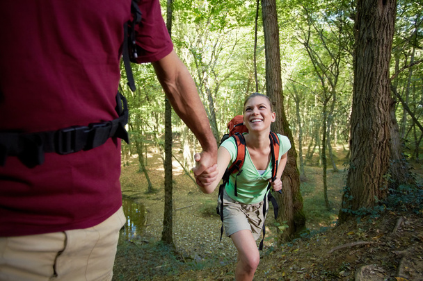 Jovem casal trekking na floresta e de mãos dadas
 - Foto, Imagem