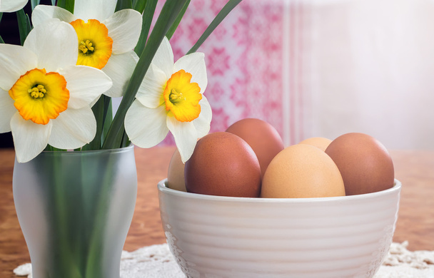 Pasen eieren in een keramische vaas en bloemen narcissen. - Foto, afbeelding