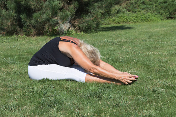 Flexible senior blonde woman is exercising outdoors - Foto, immagini