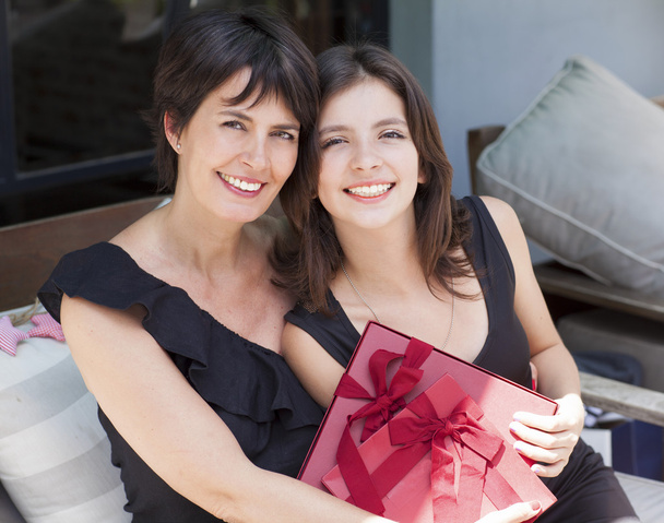 Moeder en dochter met geschenken buiten zitten - Foto, afbeelding