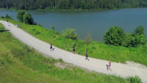 Μερικοί άνθρωποι τρέχουν γύρω από τη λίμνη - Πλάνα, βίντεο