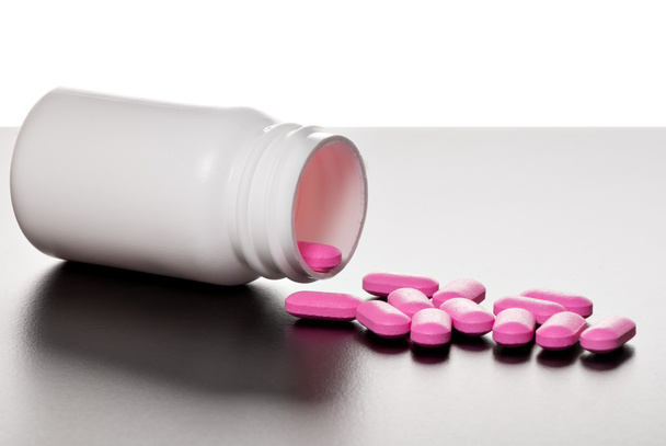 Roze tabletten met fles - Foto, afbeelding