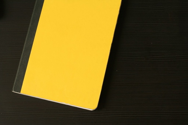 Keltainen päiväkirja (muistikirja) mustalla puupöydällä
 - Valokuva, kuva
