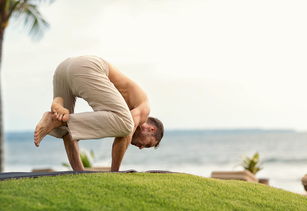Young man doing yoga on the beach - Фото, изображение