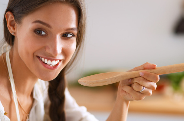 Cooking woman in kitchen with wooden spoon - Foto, imagen