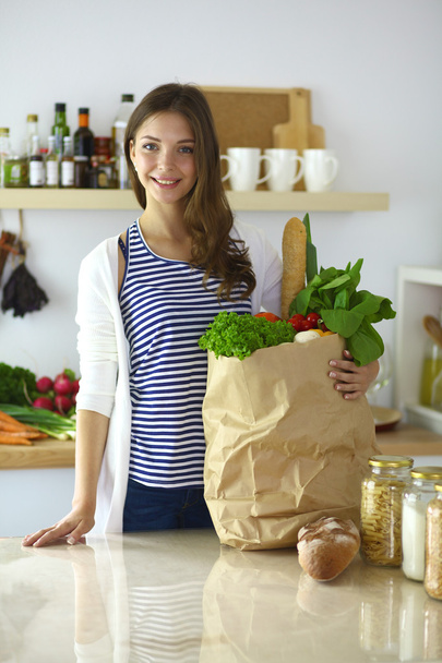 Elinde sebzeli alışveriş torbası tutan genç bir kadın. - Fotoğraf, Görsel