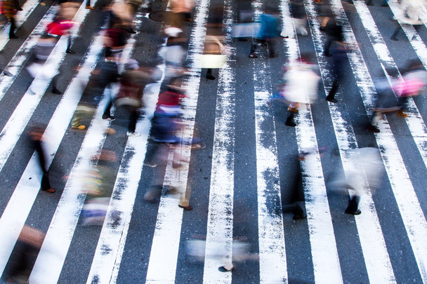 Gente cruzando un cruce de cebra con desenfoque de movimiento y enfoque a las rayas en la calle, vista de ángulo alto
 - Foto, Imagen