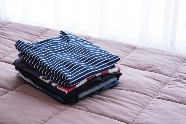 Складывание одежды на кровати перед хранением в шкафу
 - Фото, изображение