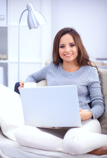Boldog szép nő használ laptop ül a kanapén - Fotó, kép
