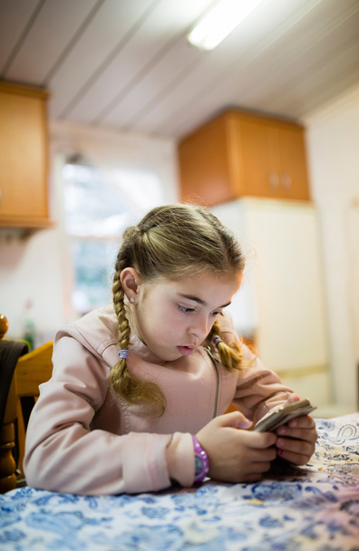 Menina loira com tranças procurando um telefone inteligente
 - Foto, Imagem