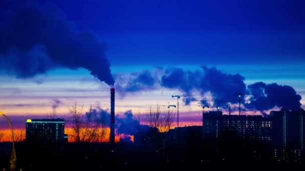 Modern city in the evening at sunset. Smoke comes out of the pipes of power plants and factories of the modern neighborhood on the outskirts of the metropolis. Urbanization. - Footage, Video