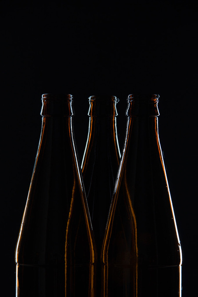 Silhouettes brown glass bottles for beer on a black background - Photo, image