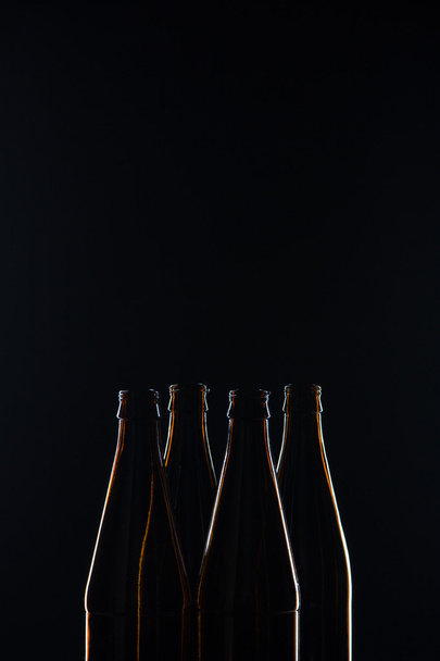 Silhouetten braune Glasflaschen für Bier auf schwarzem Hintergrund - Foto, Bild
