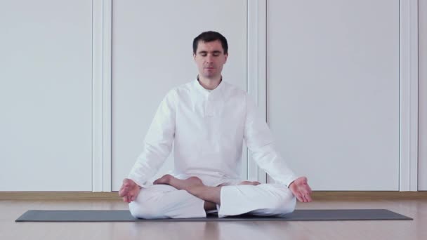 Handsome man practicing yoga in a yoga studio. Ardha Padmasana. - Footage, Video