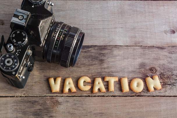 Old film dslr camera and vacation text on the wooden background - Photo, Image