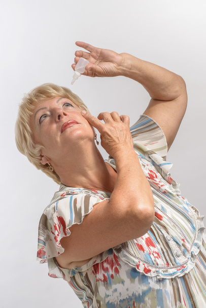 mature woman treats her eyes with drops - Photo, Image