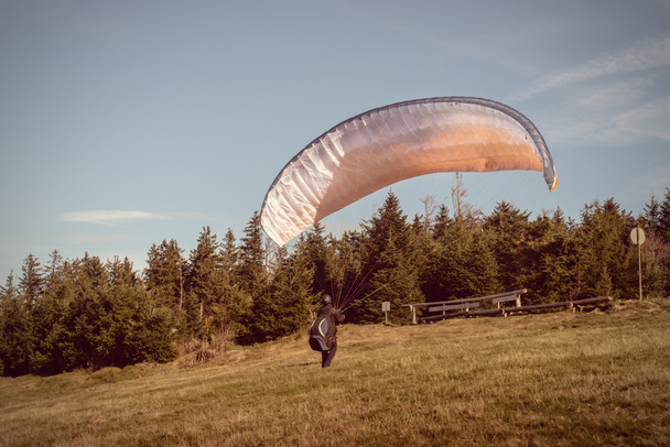 Een paraglider zich voorbereidt op de lancering van een heuveltop. - Foto, afbeelding