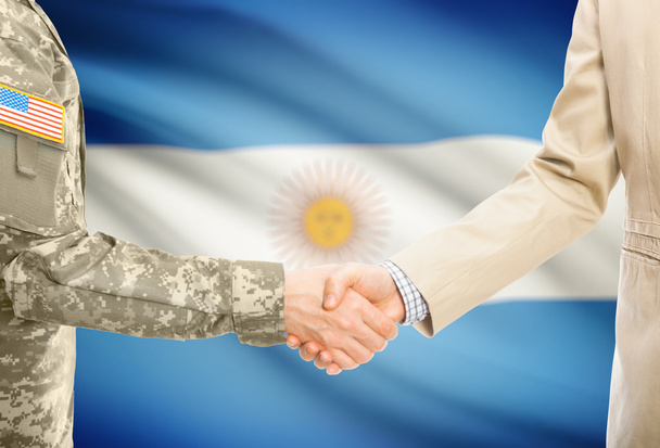 USA military man in uniform and civil man in suit shaking hands with national flag on background - Argentina - Fotografie, Obrázek