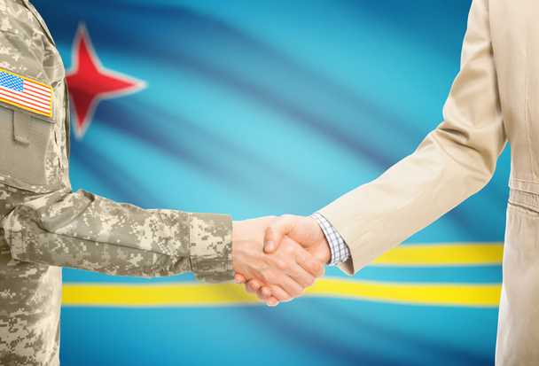 США военный человек в военной форме и гражданской мужчина в костюме, рукопожатие с национальным флагом на фоне - Аруба - Фото, изображение