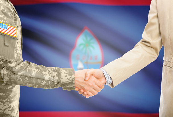USA military man in uniform and civil man in suit shaking hands with national flag on background - Guam - Fotografie, Obrázek