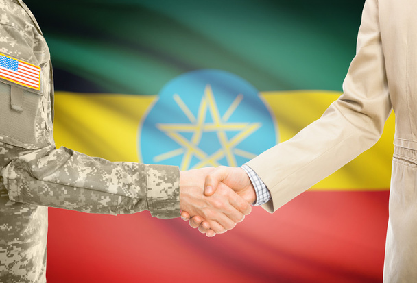 USA military man in uniform and civil man in suit shaking hands with national flag on background - Ethiopia - Fotografie, Obrázek
