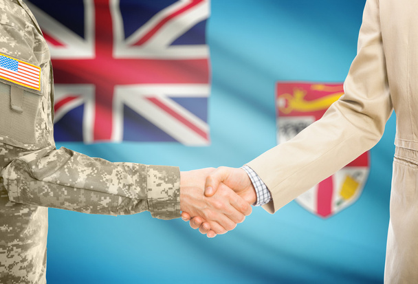 USA military man in uniform and civil man in suit shaking hands with national flag on background - Fiji - Fotografie, Obrázek