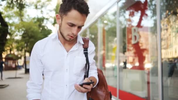Mladý muž se snaží najít kontakt na mobil. Evropského chlapík otočit stránky na smartphone. - Záběry, video