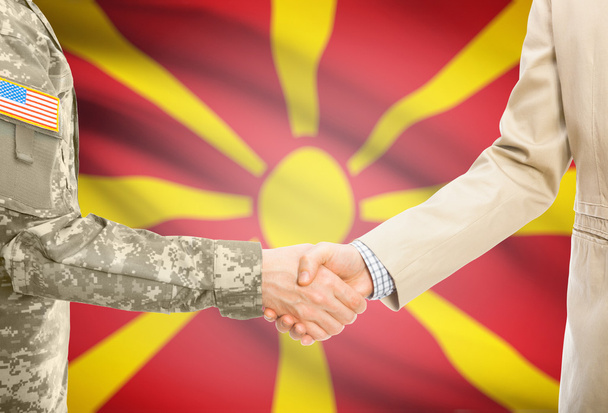 USA military man in uniform and civil man in suit shaking hands with national flag on background - Macedonia - Fotografie, Obrázek