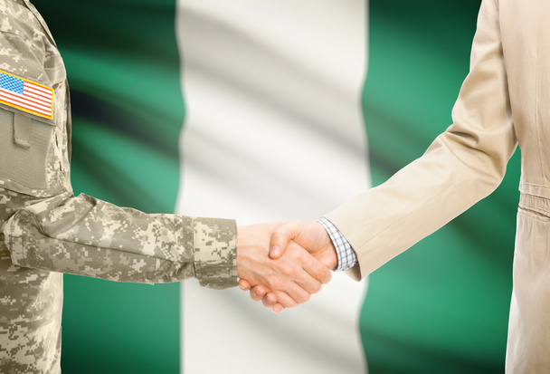 USA military man in uniform and civil man in suit shaking hands with national flag on background - Nigeria - Fotografie, Obrázek