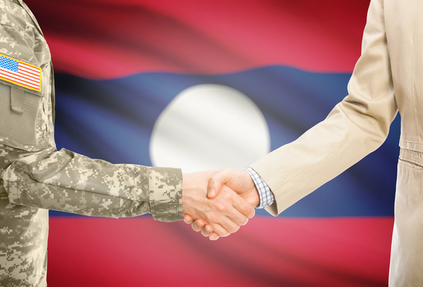 USA military man in uniform and civil man in suit shaking hands with national flag on background - Laos - Fotografie, Obrázek