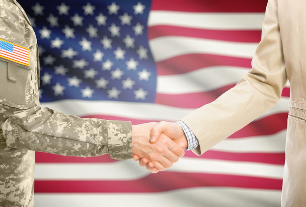 США военный человек в единообразной и гражданский человек в костюм рукопожатие с национальным флагом на фоне - Соединенные Штаты Америки - Фото, изображение