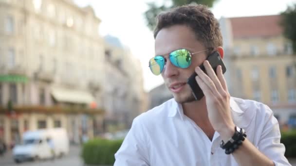 Nuori mies puhuu matkapuhelimella keskellä Euroopan kaupungin keskustaa
. - Materiaali, video