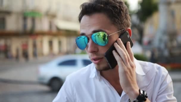 Attractive guy smiling while having a conversation on mobile phone. Close-up picture of handsome man talking on cellphone. - Кадры, видео