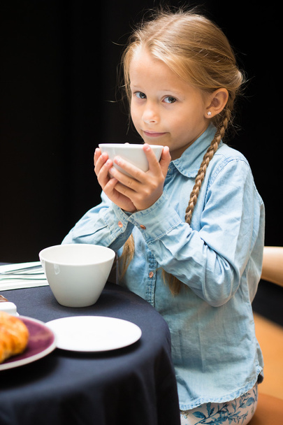Adorable little girl having breakfast at cafe - Photo, Image