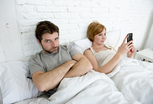 az ágyban-férje frusztrált pár ideges elégedetlen, közben felesége mobiltelefon használata  - Fotó, kép