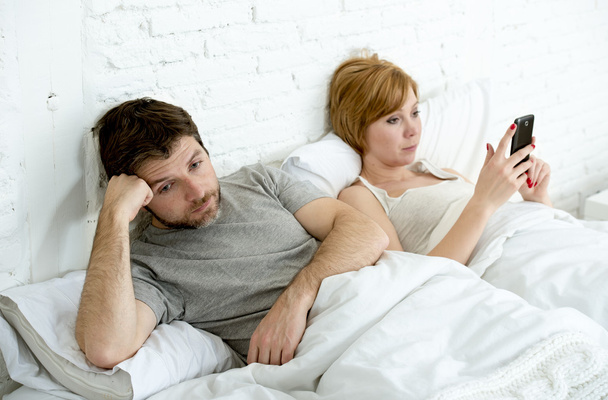 pareja en la cama marido frustrado molesto e insatisfecho, mientras que su adicta a Internet esposa está utilizando el teléfono móvil
 - Foto, Imagen
