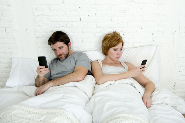 Młoda para przy użyciu telefonu komórkowego w łóżku ignorowanie siebie w relacji problemy komunikacyjne - Zdjęcie, obraz