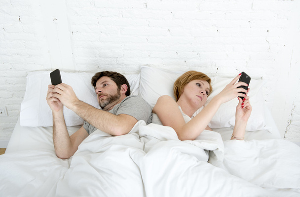 Młoda para przy użyciu telefonu komórkowego w łóżku ignorowanie siebie w relacji problemy komunikacyjne - Zdjęcie, obraz