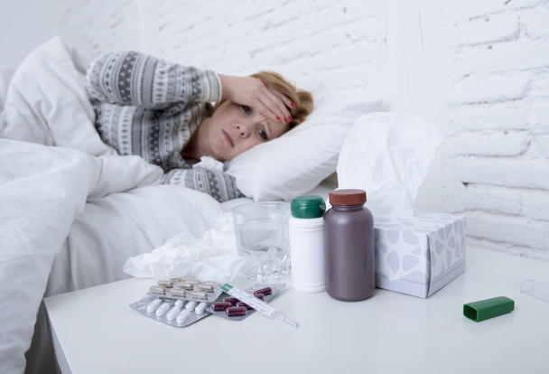  Kranke Frau, die sich schlecht fühlt, liegt krank im Bett und leidet unter Kopfschmerzen, Winterkälte und Grippeviren mit Medikamenten - Foto, Bild