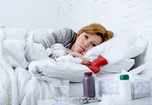 young sick woman lying on bed ill feeling bad looking feverish and weak suffering winter flu virus - Foto, imagen